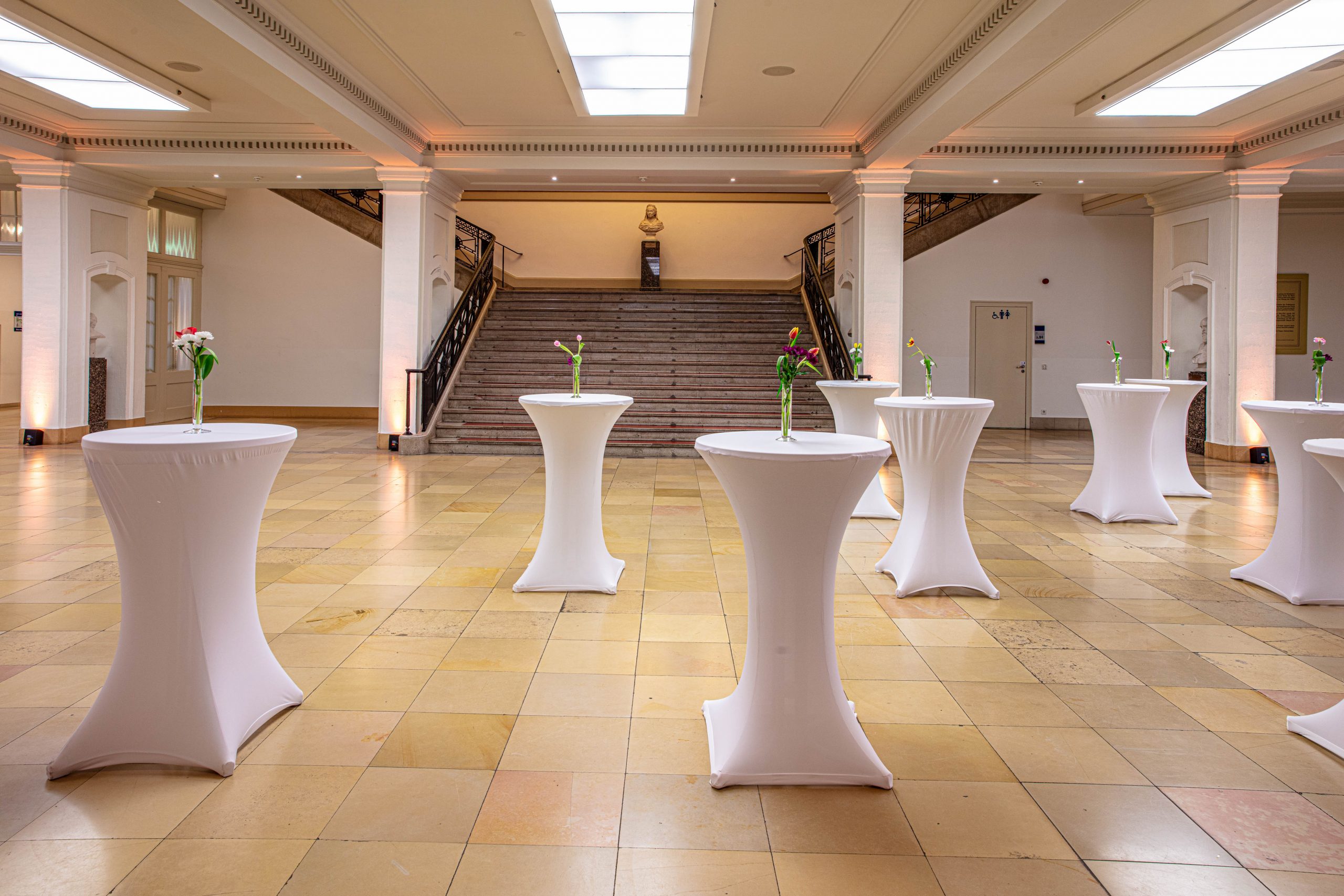 Foyer im Erdgeschoss des LVH Langenbeck Virchow Haus Berlin mit Marmorboden und weißen Stehtischen für Empfänge und Veranstaltungen