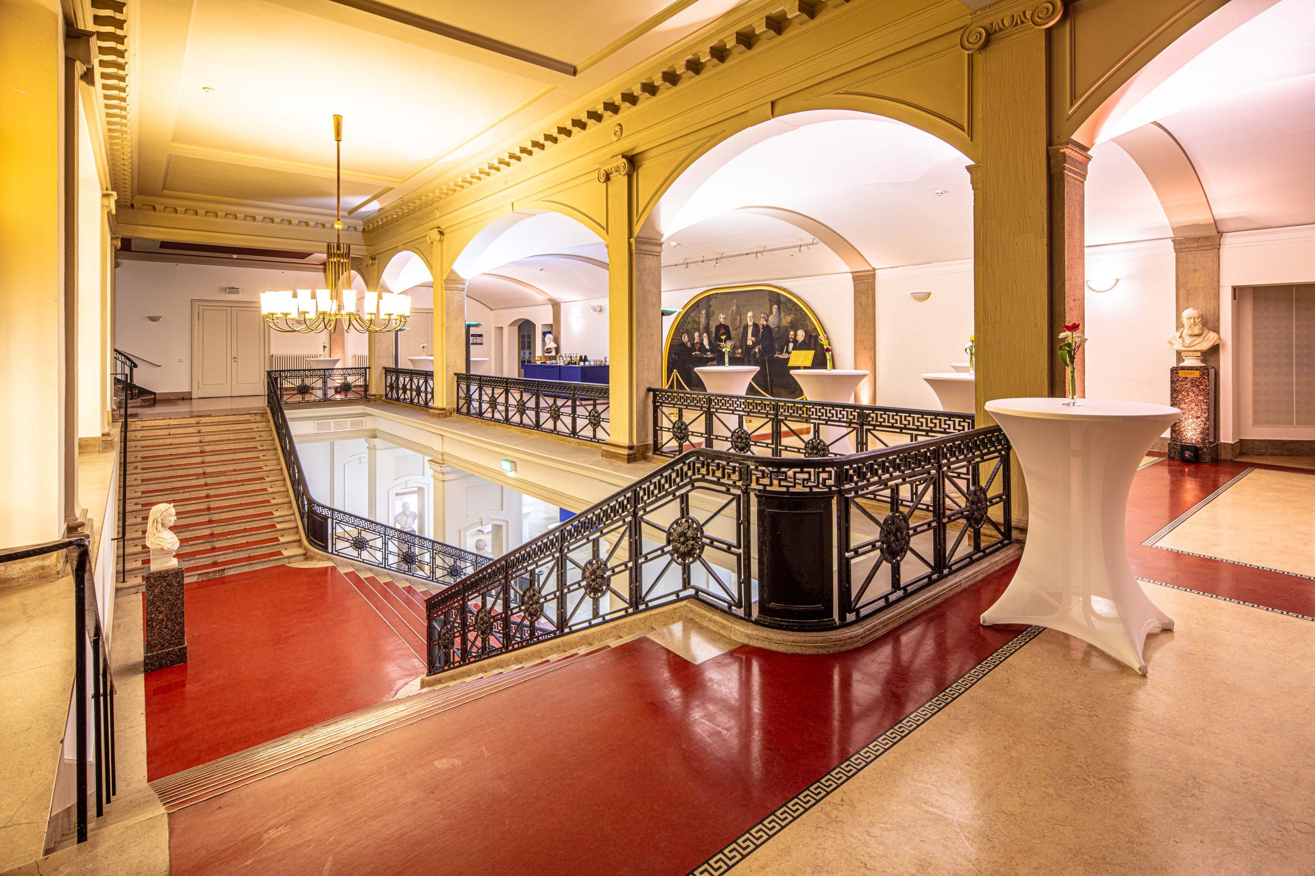 Historische Wandelhalle im LVH Langenbeck Virchow Haus Berlin mit roten Böden, Geländern und Stehtischen für Veranstaltungen