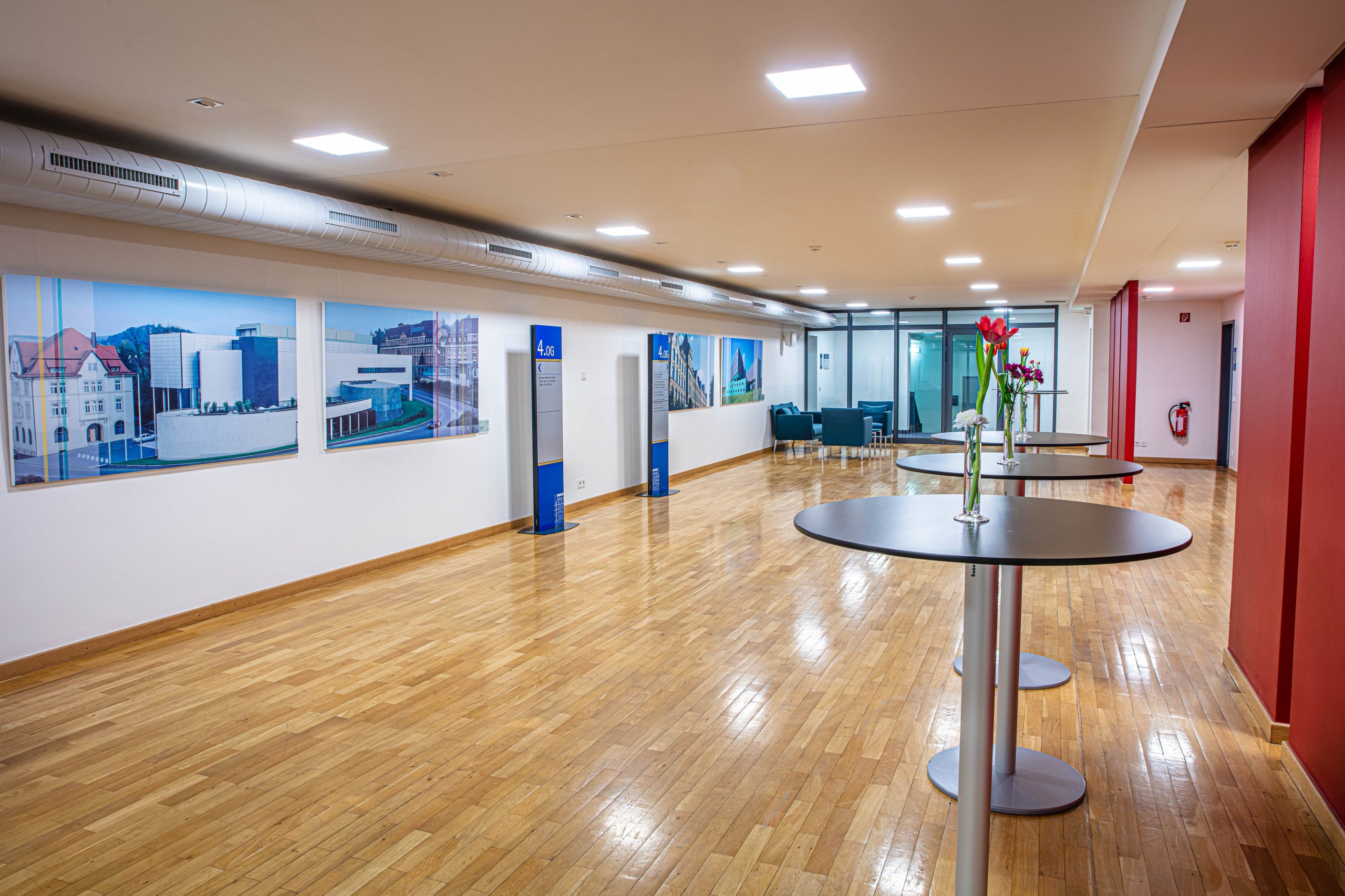Foyer 4. Obergeschoss im Langenbeck-Virchow-Haus Berlin mit Stehtischen, roter Wandgestaltung und großformatigen Bildern an den Wänden